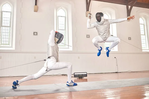 Jump, fencing and people with sword to fight in training, exercise or workout in a hall. Martial arts, sports and fencers or men with mask and costume for fitness, competition or target in swordplay.