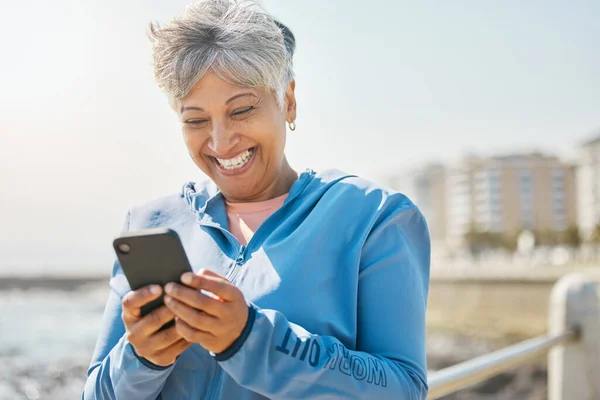 フィットネス ビーチ シニアの女性と携帯電話 幸福とソーシャルメディアとネットワーク 電子メールと笑顔 スマートフォン シーサイド メッセージ付きのハッピーパーソン 高齢女性 — ストック写真