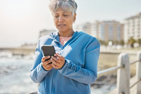 ランニング トレーニング 結果のためのビーチで古い女性とのニュース フィットネス テクノロジー スポーツ モバイルアプリのための自然の中で女性ランナーのトレーニングとのネットワーク コミュニケーションと連絡 — ストック写真