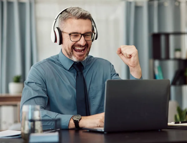 stock image Celebrate, headphones and businessman working on a laptop with good news or achievement. Happy, excited and mature professional male designer in celebration for job promotion or success in workplace