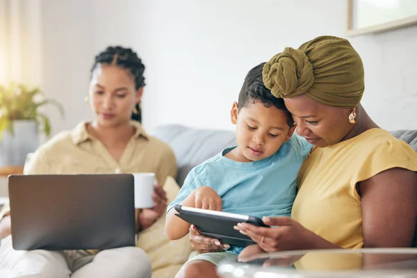 stock image Technology, tablet and family child, mom or black woman reading online ebook, e learning and remote education. Studying, lesbian mothers or relax gay people teaching kid on home living room couch.