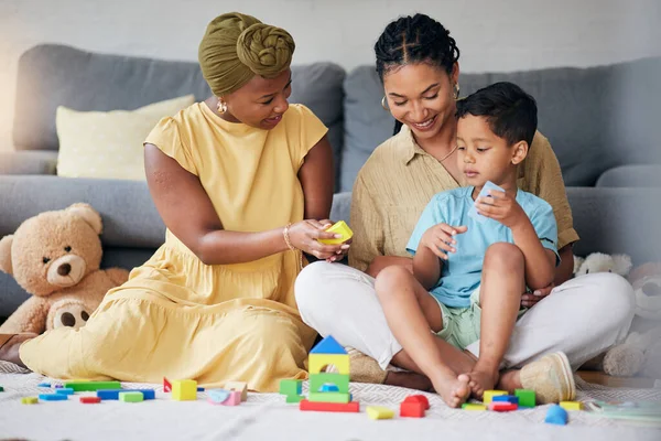 stock image Toys, child and a gay family playing on a home floor for development, education and learning. Adoption, lesbian or LGBT women or parents and kid together in a lounge for quality time with fun blocks.