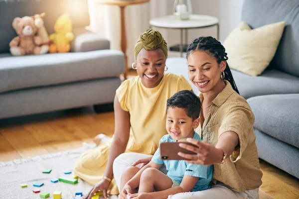 stock image Lesbian, women and son in home for selfie, smile or care with toys, post or blog on floor in living room. Mother, male kid and happy for gay love, bonding and memory on social network in family house.