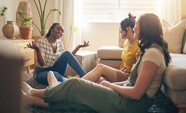 Happy, gossip and friends on a floor relax, talking and bond with advice in house together. Conversation, drama and women with diversity in a living room speaking, chilling and enjoy weekend freedom.