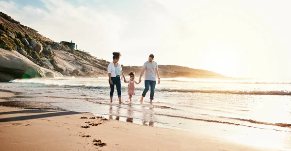 Bonding, sunset and family on the beach for vacation, adventure or holiday together for bonding. Travel, walking and girl child with her mother and father on the sand by the ocean on a weekend trip