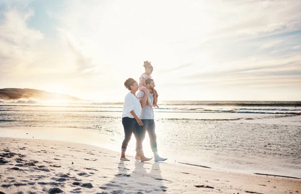Walking, sunset and family on the beach for vacation, adventure or holiday together for bonding. Travel, having fun and girl child with her mother and father on the sand by the ocean on weekend trip