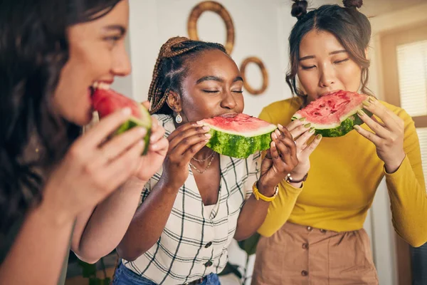 Women, friends and eating watermelon in home for bonding, nutrition and happy lunch together. Healthy diet fruit, sharing and wellness, fresh summer food for friendship and girls in kitchen at party