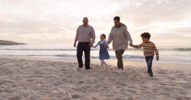 Walking, children and grandparents holding hands at beach for fun vacation, holiday or adventure at sunset. Senior man, woman and kids together at ocean for family time with love outdoor in nature.