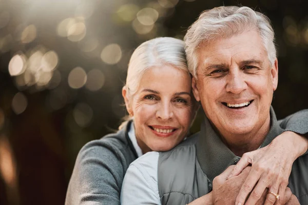 stock image Love, portrait and senior couple hug at a park happy, free and enjoy travel, holiday or weekend. Face, smile and elderly woman embrace man in forest, bond and having fun on retirement trip together.