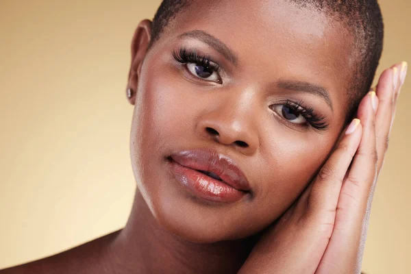 Beauty, natural makeup and face of a black woman in studio with hands on skin care, glow and cosmetics. Portrait of african person or model with facial shine and wellness on a beige background.
