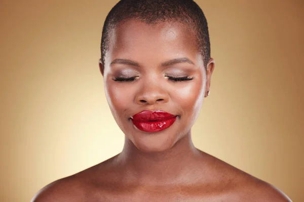 Red lipstick, makeup and a black woman with beauty in studio or skin care, glow and cosmetics. Face of an African person or model with facial shine, dermatology and wellness on a beige background.
