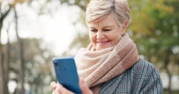 通信和一位资深女士在公园里 寻找社交媒体在应用程序上的位置 与一位快乐的老年女性一起在室外花园看短信 在手机上微笑 发短信 — 图库视频影像