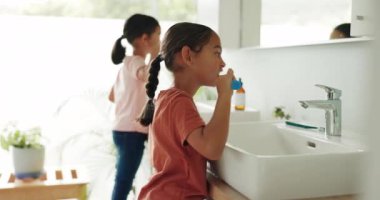 Çocuklar modern aile evlerinin banyosunda diş bakımı için dişlerini fırçalıyorlar. Hijyen, ağız sağlığı ve kız çocukları evlerinde sağlıklı olmak için sabah ağızlarını temizliyorlar.