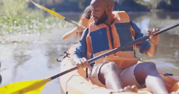 カヤック フィットネス アドベンチャーのために湖のカップルと混同 スポーツ アクション ローイングのための森でカヌーボートで黒人男性と女性との休暇 旅と持続可能性 — ストック動画