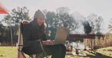 Kamp, sabah ve bir kadın laptopunu doğada gezmek ya da macera yaşamak için kullanıyor. Bilgisayar, yürüyüş ve özgürlük. Ormanda kış tatili boyunca internette gezinen bir kızla..