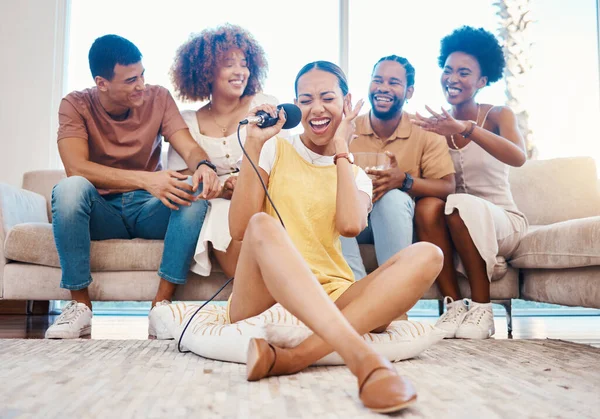 Microphone, happy or friends singing in home living room together in a party on holiday vacation break. Girl singer, men or group of funny women laughing to relax in a fun karaoke competition or game.