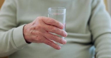 Sağlık, el ya da yaşlı bir adam sağIık ya da susuzluk için su içiyor. Evde romatizma yüzünden rahatlıyor. Parkinson, cam yakın çekim ya da sağlıklı ya da taze su ile susamış yaşlı kişi canlılık için.