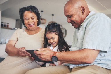 Mutlu bir aile, çocuk ya da büyükanne ya da büyükbaba evde öğrenim görmek ya da eğitim almak için tablet kullanıyor. Geliştirme, büyükbaba ya da büyükanne ve kız online kitap okuyor ya da oyun oynuyorlar..