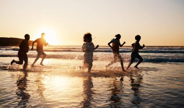 Gün doğumu, plaj ve özgürlük, yaz tatilinde birlikte suda koşmak ve eğlenmek. Okyanus, siluet ve Bali 'de tatil, bağ ve seyahat kutlamaları için denizde bir grup insan..