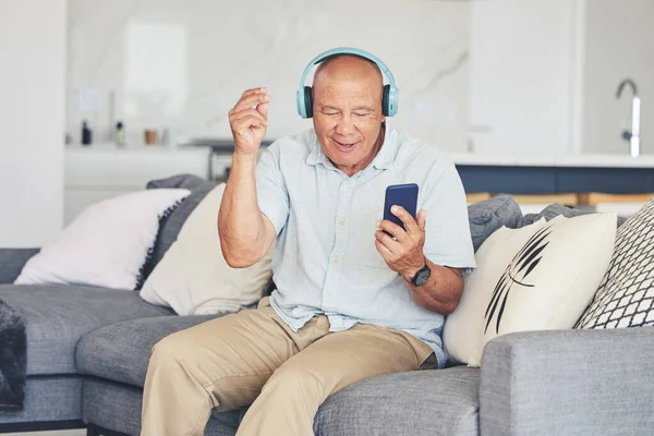 电话以及客厅里的老人在沙发上跳舞 听着收音机 放松一下 快乐而兴奋的老年人 坐在沙发上 拿着手机 在网上退休 — 图库照片