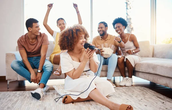 Microphone, happy people or woman singing in home living room together in party on holiday vacation break. Girl singer, men or group of funny women laughing in a fun karaoke game with popcorn snacks.