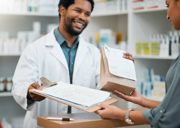 薬局の署名 処方または相談のためのクリップボードが付いている幸せな薬剤師 ペーパー袋および患者 病気の顧客に薬を与える黒人男性 医療または医療専門家 — ストック写真