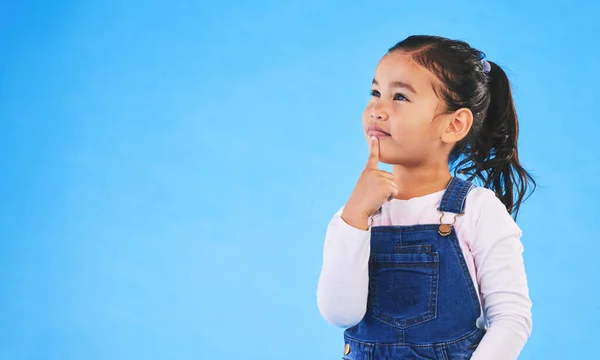 stock image Thinking, child and girl with ideas, solution and question with doubt on a blue studio background. Mockup space, kid or model with planning, choice and inspiration with problem solving or opportunity.