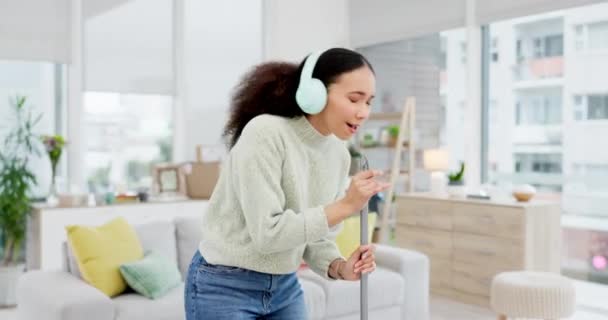 음악과 거실에서 빗자루와 헤드폰과 그녀의 집에서 하루에 노래방과 여성은 청소하는 — 비디오