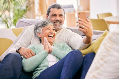 Gülüşmeler, selfie ve koltukta telefon, sosyal medya veya video görüşmesi için yaşlı bir çift. Gülümse, ev ve kanepede cep telefonuyla fotoğraf çeken yaşlı bir adam ve kadın..
