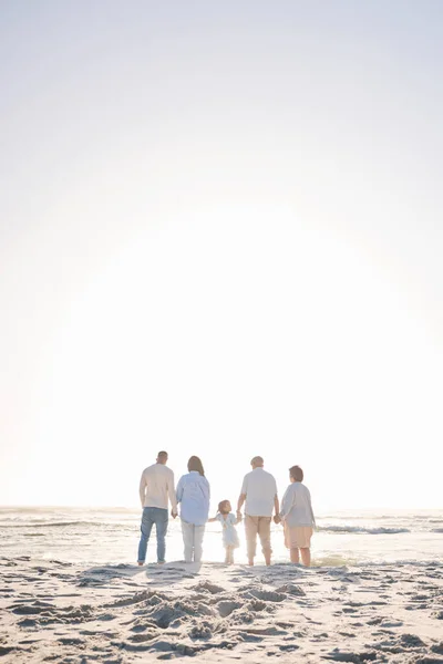 Love, travel and holding hands with big family on beach for vacation, bonding and summer. Freedom, care and relax with group of people walking at seaside holiday for generations, happiness and mockup.