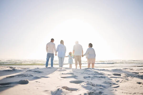 Summer, travel and holding hands with big family on beach for vacation, bonding and love. Freedom, care and relax with group of people walking at seaside holiday for generations, happiness and mockup.