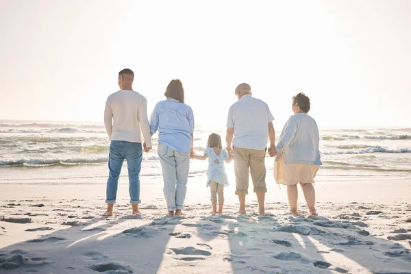 Summer, relax and holding hands with big family on beach for vacation, bonding and love. Freedom, care and travel with group of people walking at seaside holiday for generations, happiness and mockup.