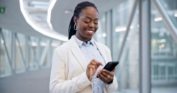 ホテルロビー ビジネスオフィスで入力するウォーキング 黒人女性 ハッピー スマートフォン アフリカのコンサルタントがソーシャルメディア モバイルネットワーキング インターネットアプリでメールを読む — ストック動画