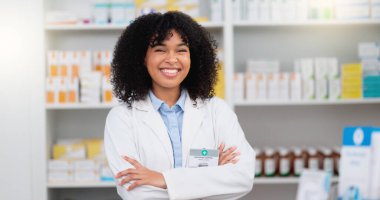 Portrait of a pharmacist with folded arms against a background of prescription medication. Happy young professional health care worker waiting to diagnose and prescribe pills at a clinic dispensary. clipart