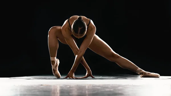 Art, ballet and woman on black background stretching in dance performance with balance, stage and talent. Dark aesthetic, flexible ballerina or dancer with fitness, creativity and studio exercise