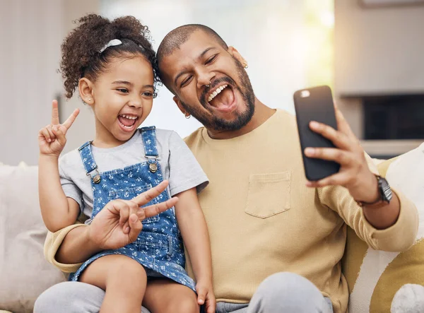 Father, girl and peace sign selfie in home living room, bonding and funny together. Dad, child and excited in v hand on profile picture, happy memory or social media post of family laughing on sofa.