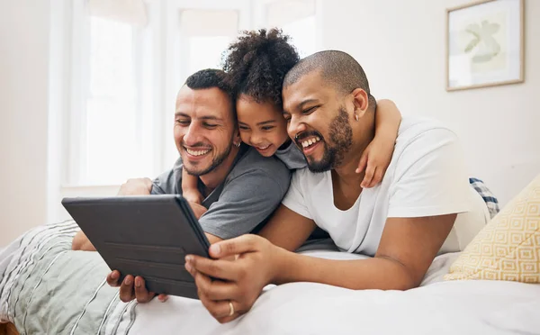 Child, gay family and tablet on bed at home for e learning, watch video and education on internet. Adoption, lgbt men or parents with happy kid and technology for streaming movies, games or funny app.