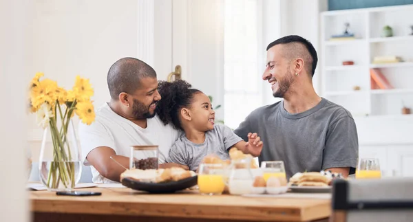 Happy, gay men and family at breakfast together in the dining room of their modern house. Smile, bonding and girl child eating a healthy meal for lunch or brunch with her lgbtq dads at home