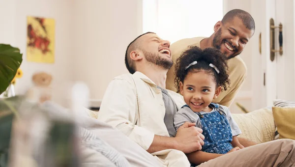 Gay family, laughing and a child on a home sofa with love, care and funny joke in lounge. Lgbtq men, adoption and parents with foster girl kid together on a couch for happiness, bonding and to relax.