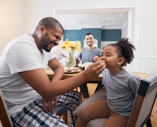 Gay couple, breakfast and dad feeding kid meal, food or cereal for morning wellness, care and youth development support. Family, adoption and non binary father smile for hungry child eating at home.