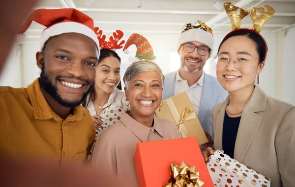 Business people, Christmas selfie and group with smile, present or portrait for celebration, diversity or party. Men, women and photography for xmas memory, friends and gift box for workplace culture.