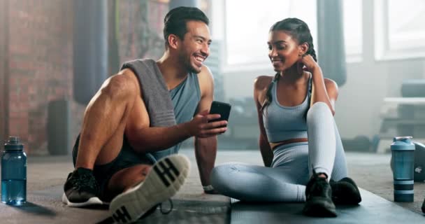 情侣朋友 电话和健身训练支持 滑稽迷因或社交媒体检查和在线阅读在健身房 快乐的男人 女人或私人教练在地板上放松一下 进行锻炼谈话 — 图库视频影像