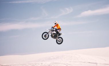 Motosiklet, gökyüzü ve çölde bir adamla macera ya da adrenalin için bir araca atlamak. Bisiklet, hız ve kum üzerinde özgürlük veya aktif rekabet için havada bir sporcuyla antrenman.