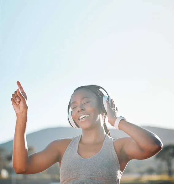 Headphones, dancing and black woman at fitness training or outdoor workout for health wellness and enjoy music. Smile, African and athlete or person streaming audio or radio for exercise in a park.