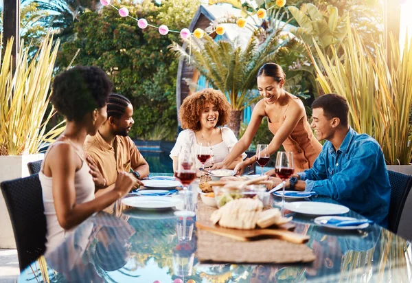 Friends, food and people outdoor at a table for social gathering, happiness and holiday celebration. Diversity, men and women group eating lunch at party or reunion with drinks to relax in a garden.