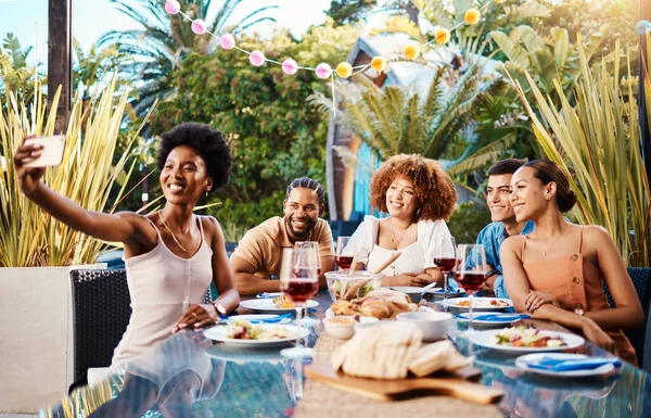 Friends in selfie at lunch, party in garden and happy event with diversity, food and wine, outdoor bonding together. Photography, men and women at dinner table, people eating with drinks in backyard