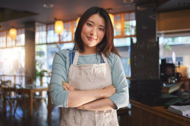 Portre, Asyalı kadın ve profesyonel hizmet için kollarını kavuşturmuş küçük bir restoran girişimcisi. Kafeterya garsonu, kahvehane garsonu ya da konukseverlikte çalışan kendine güvenen yönetici..