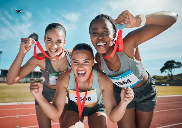 Happy women, medal and celebration in olympic winning, running or competition together on stadium track. Group portrait of athletic people in happiness, award or victory in sports marathon or success.