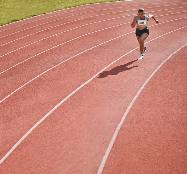 Woman, athlete and running on stadium in fitness, workout or cardio exercise for practice or training on track. Female person or runner in sport competition, performance or race in outdoor motivation.