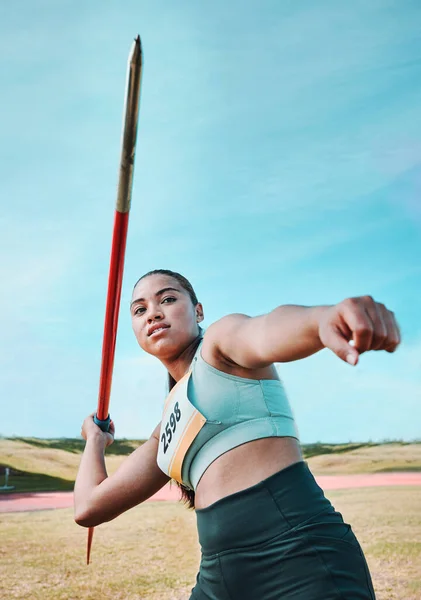 Woman, javelin and olympic athlete in competition, practice or sports training in fitness on stadium field. Active female person or athletic competitor throwing spear, poll or stick in distance.